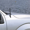 A close-up of a black replacement antenna mast mounted on the roof of a white Ford F-150 truck.
