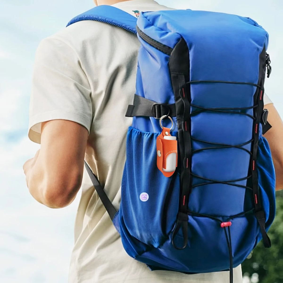 A person is wearing a blue portable inhaler storage case backpack with an orange keychain attached.