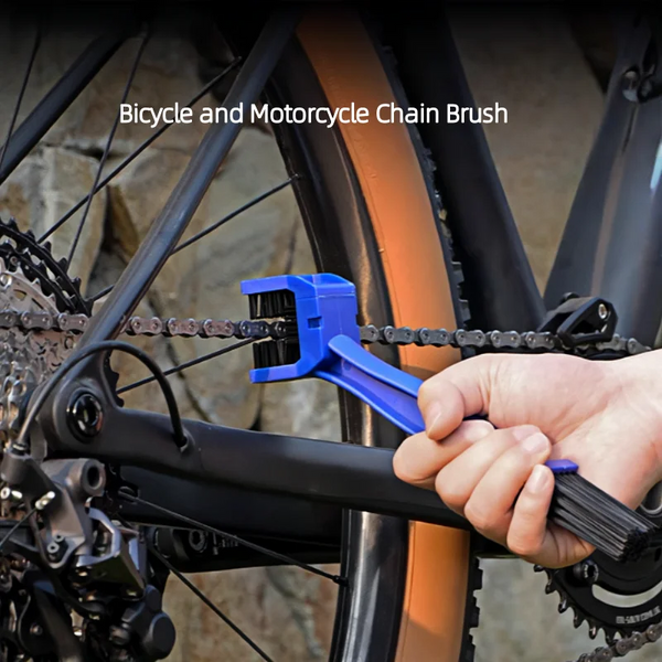 Eine Hand hält einen blauen Fahrrad- und Motorkettenbürsten neben einer Fahrradkette.