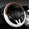 A close-up view of a white leather steering wheel cover with brown stitching and a black center hub in a car interior.