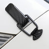 Black carbon fiber pull buckle repair clips attached to a white car surface.