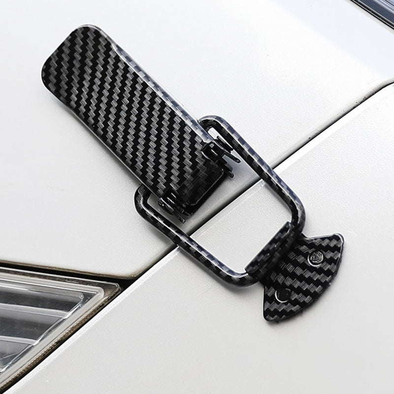 Black carbon fiber pull buckle repair clips attached to a white car surface.