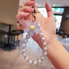 A hand holds a phone anti-loss lanyard featuring a flower pendant made of translucent beads.