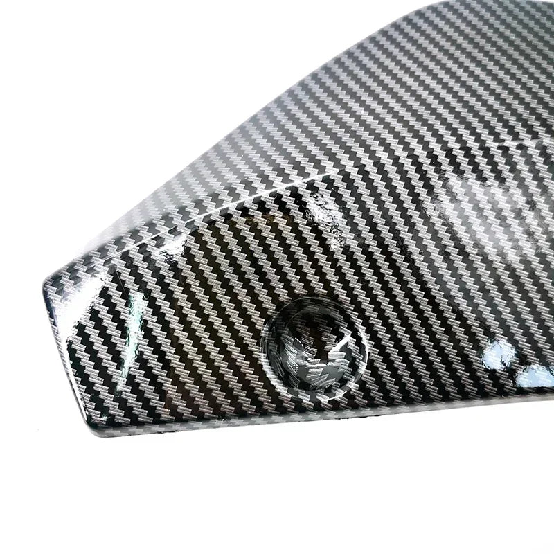 Close-up view of a carbon fiber bumper lip spoiler with a black and white weave pattern.