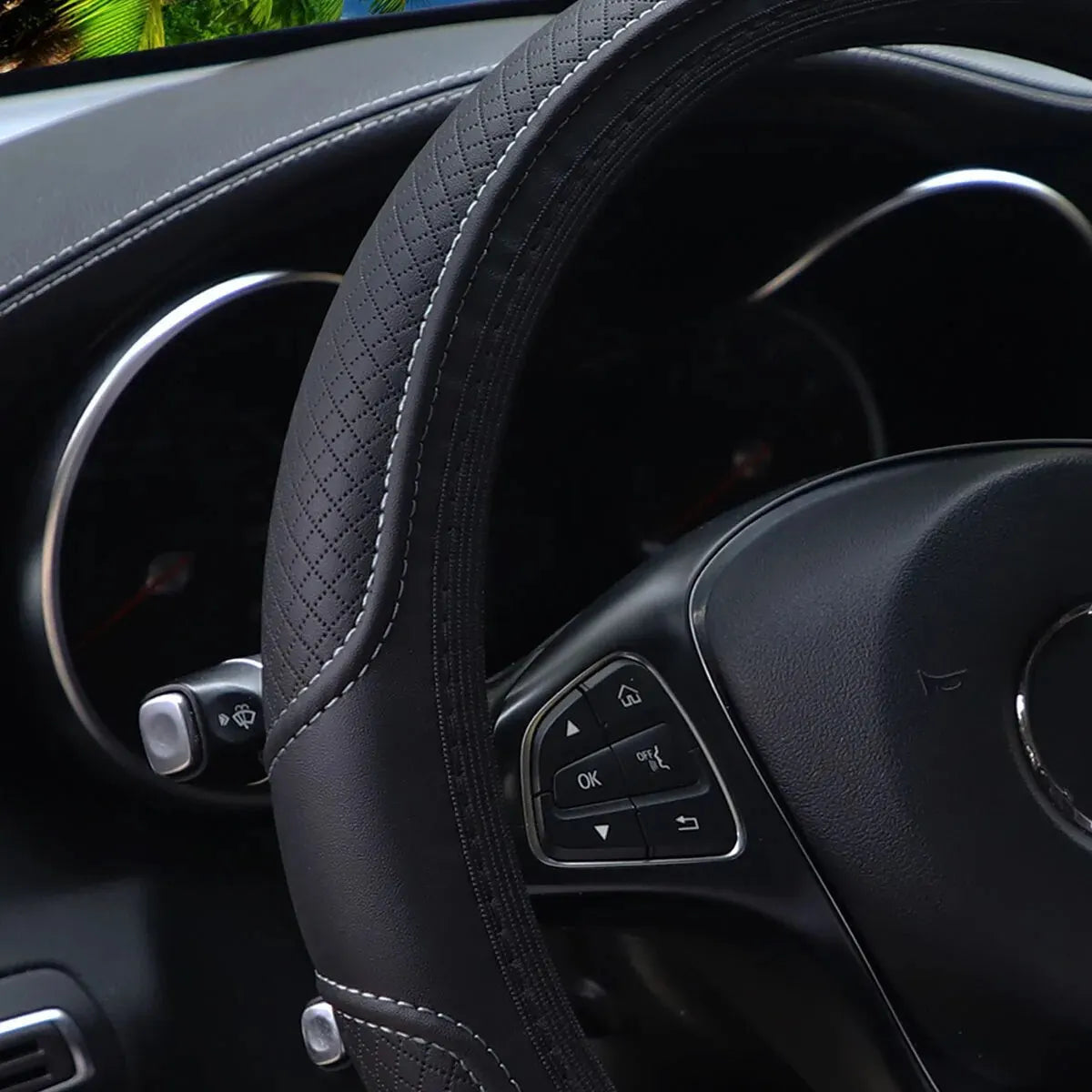 Close-up view of a black embossed leather steering wheel cover inside a car