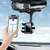 A hand holds a smartphone attached to a universal car phone mount with a retractable clip installed on a vehicle's rearview m