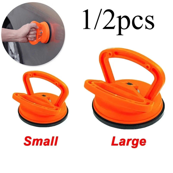Two orange car dent glass suction removal tools, small and large sizes, shown with a hand for scale.