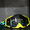 A pair of bright yellow and black high-performance motocross goggles resting on a dark surface.