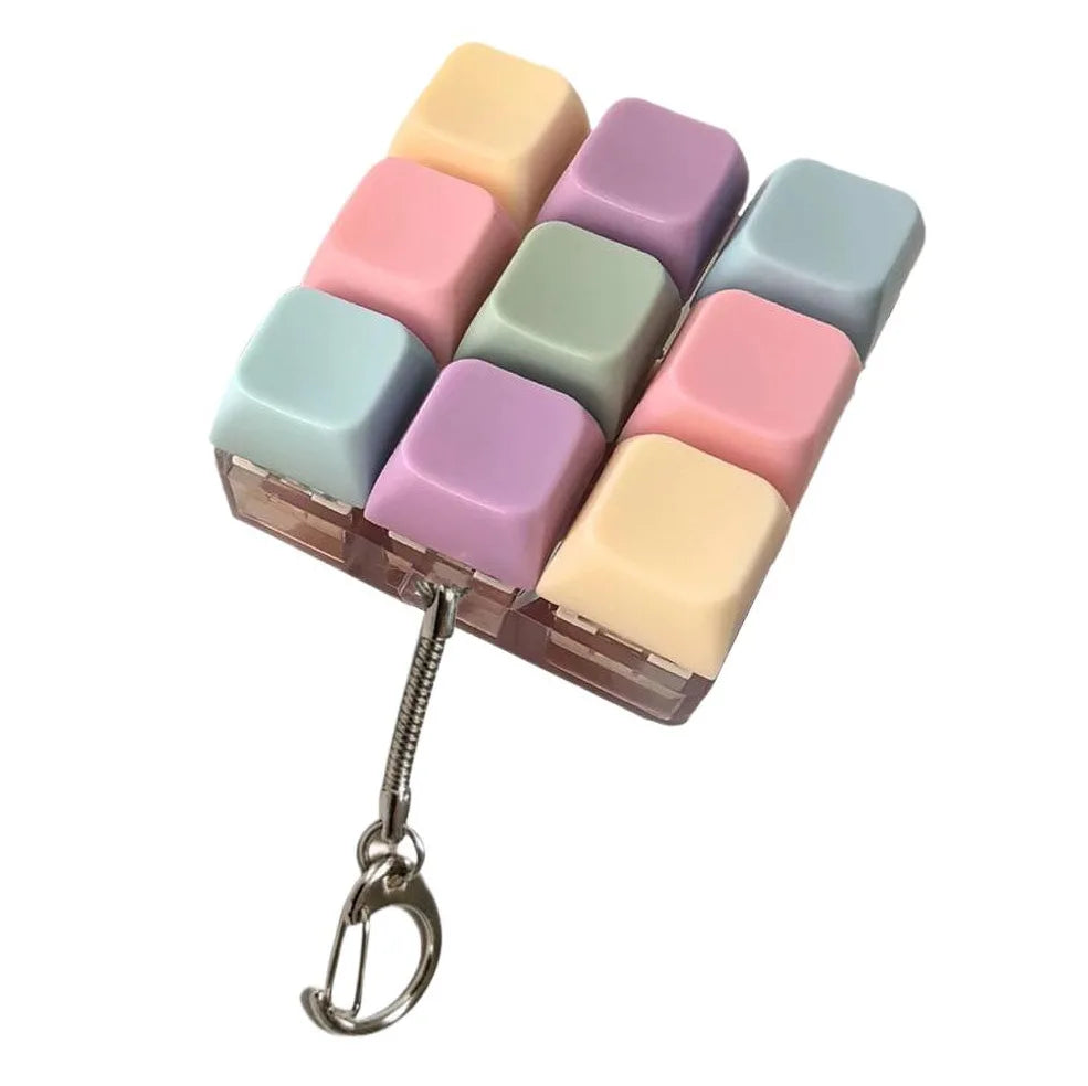 A colorful silicone fidget toy shaped like a keyboard, featuring pink, purple, and mint green keys, attached to a metal keych