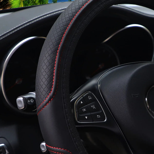 Close-up view of a black PU leather embossed steering wheel cover with red stitching and controls.