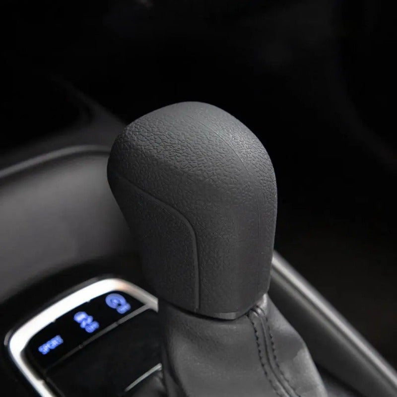 Close-up of a black gear shift knob cover on a car steering column.